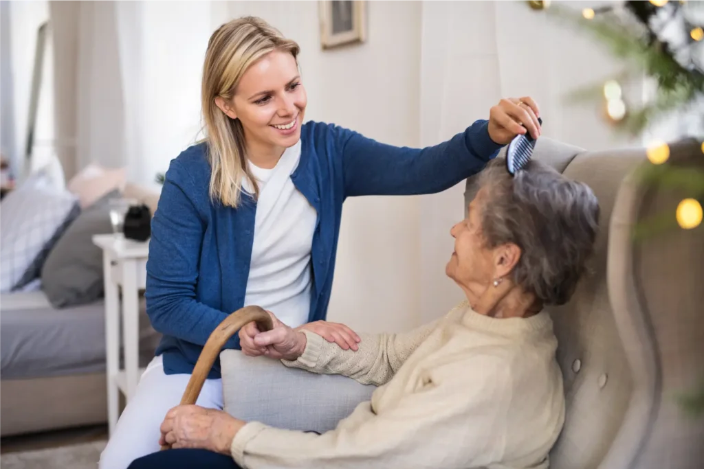 Carer assisting elderly woman with hair brushing and personal care at home in Sussex and Surrey