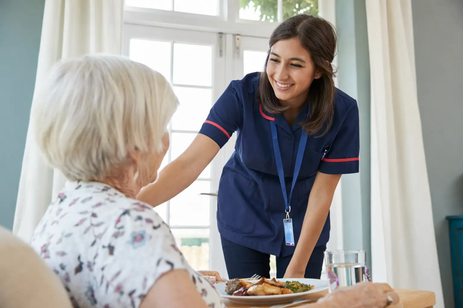 Carer assisting elderly woman with meal support and daily living at home in Sussex and Surrey