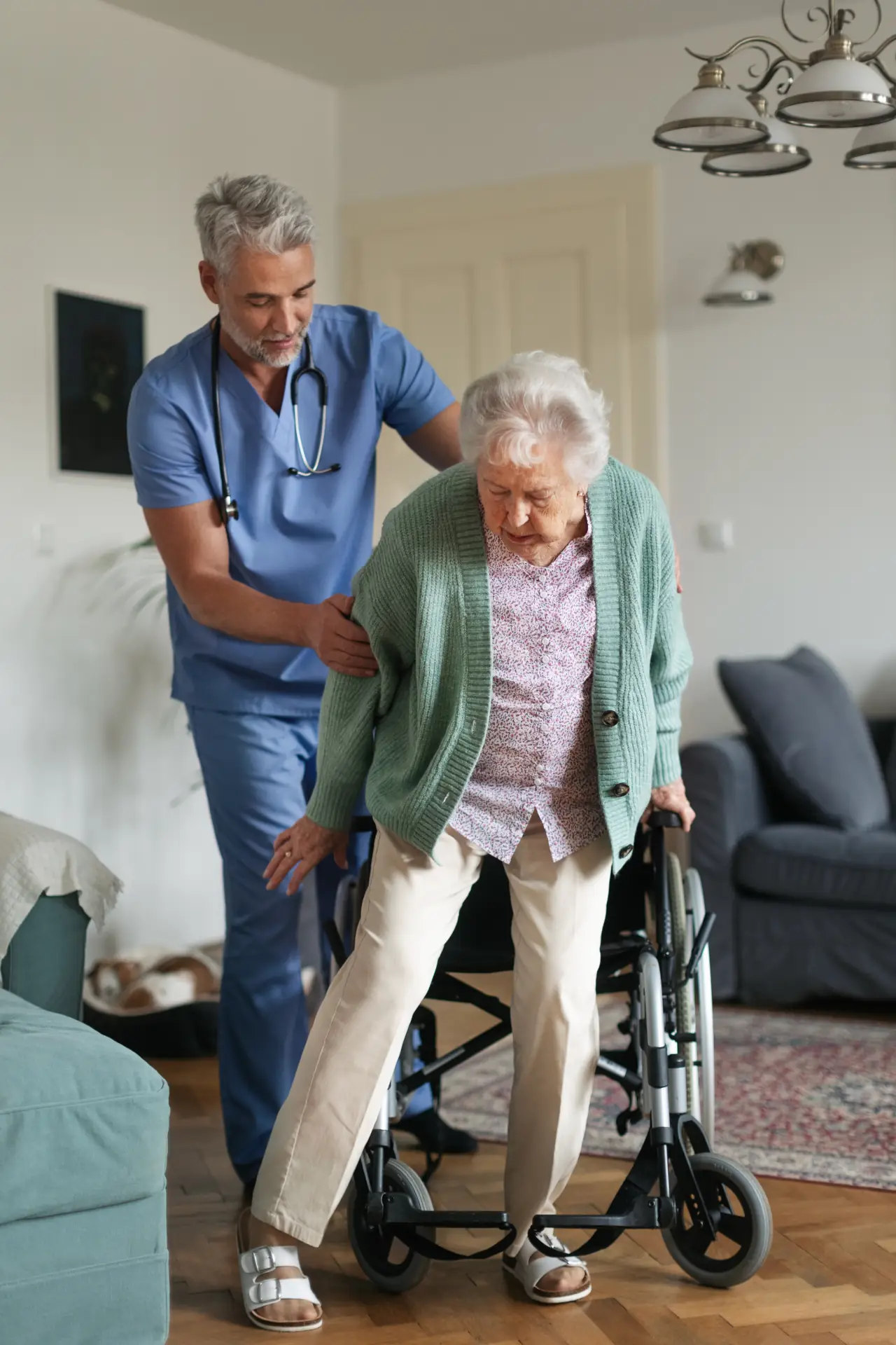 Caregiver assisting an older adult with safe mobility and standing support at home
