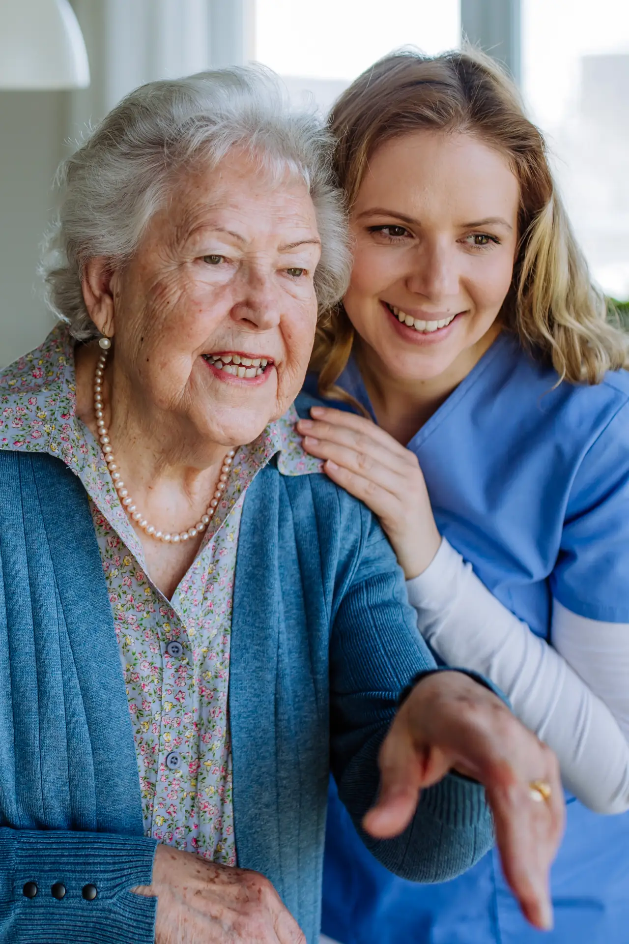 Compassionate caregiver supporting elderly woman at home