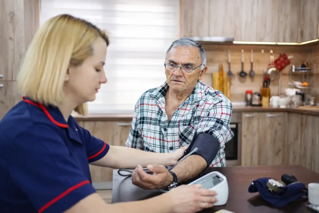 Nurse checking blood pressure of elderly man at home in Sussex and Surrey