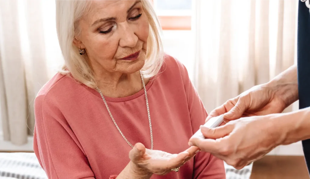 Nurse checking blood glucose levels of elderly woman at home in Sussex and Surrey