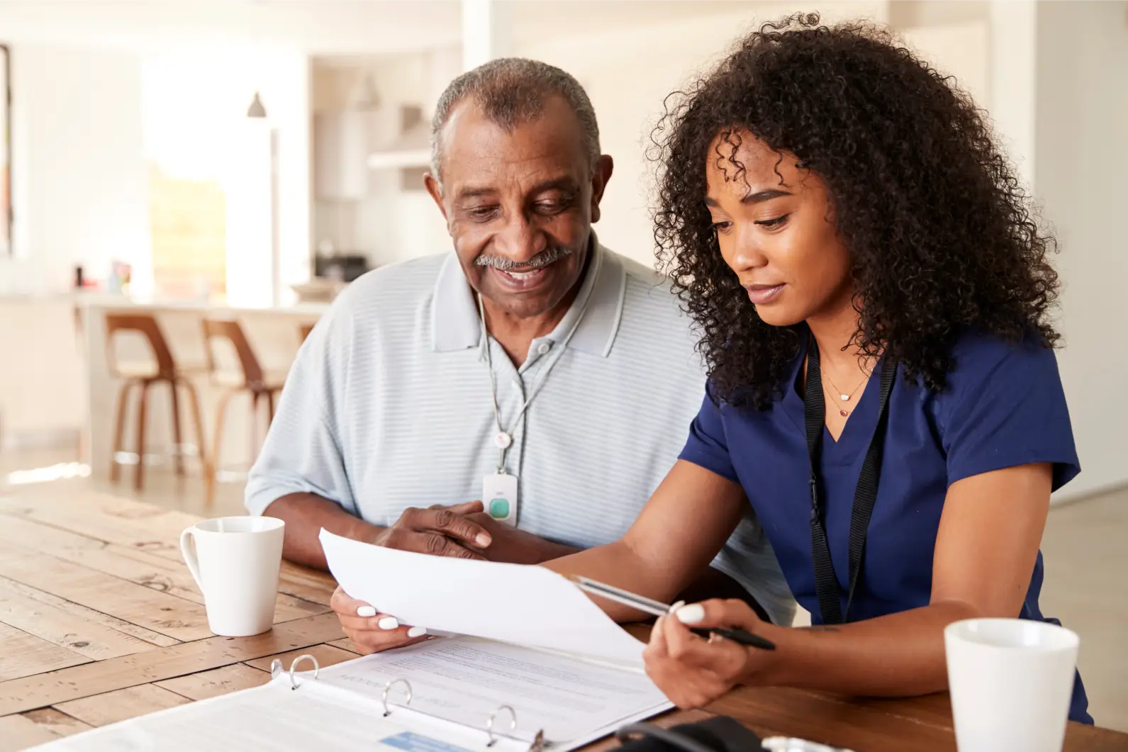 Nurse reviewing care plan and paperwork with elderly man at home in Sussex and Surrey