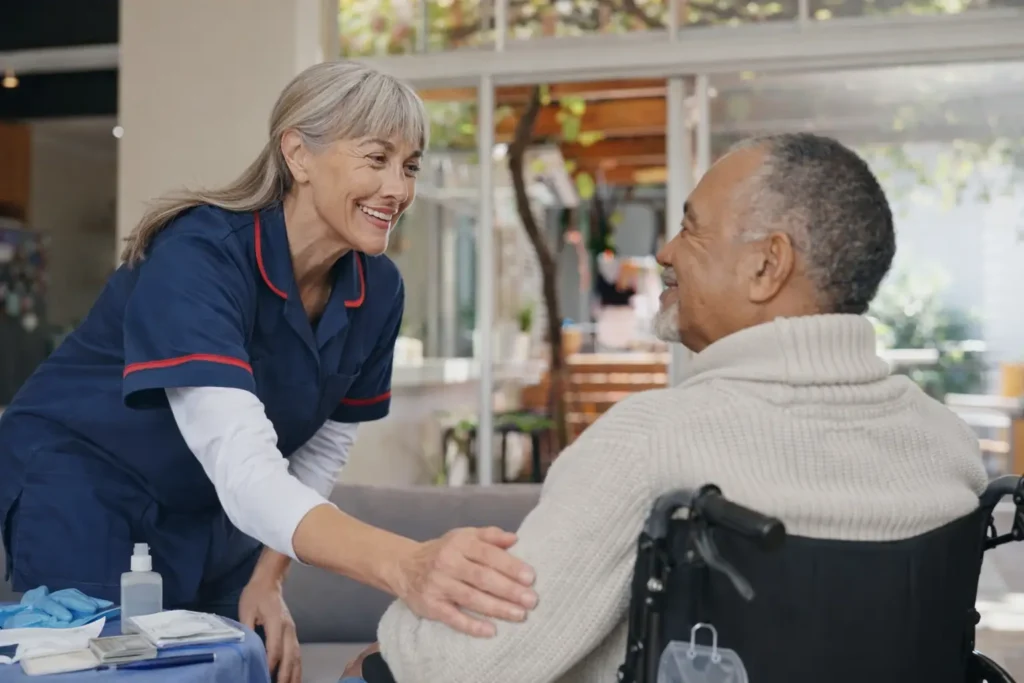 Nurse supporting elderly man in wheelchair with mobility care at home in Sussex and Surrey