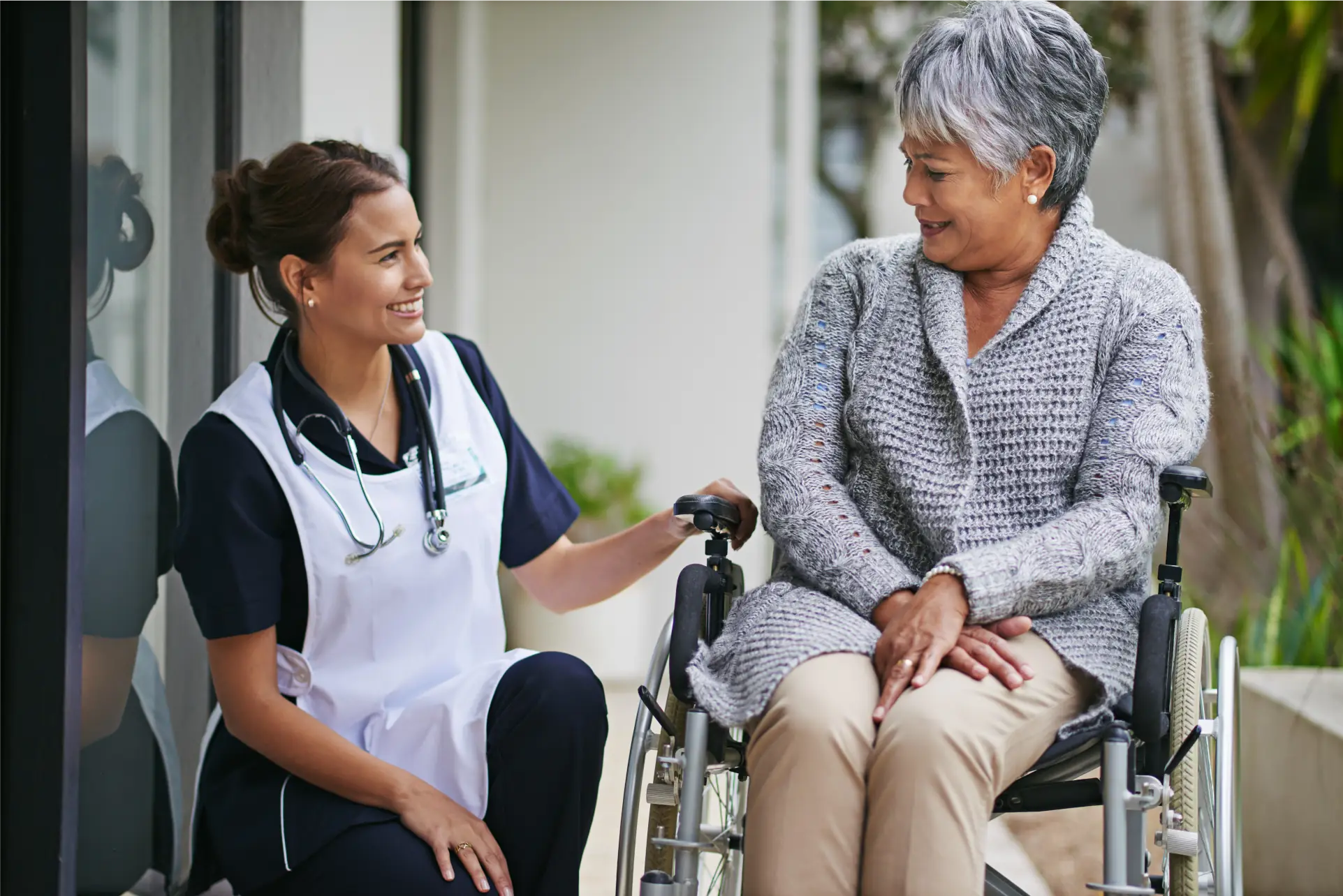 Nurse supporting elderly woman in wheelchair with mobility and outdoor care in Sussex and Surrey
