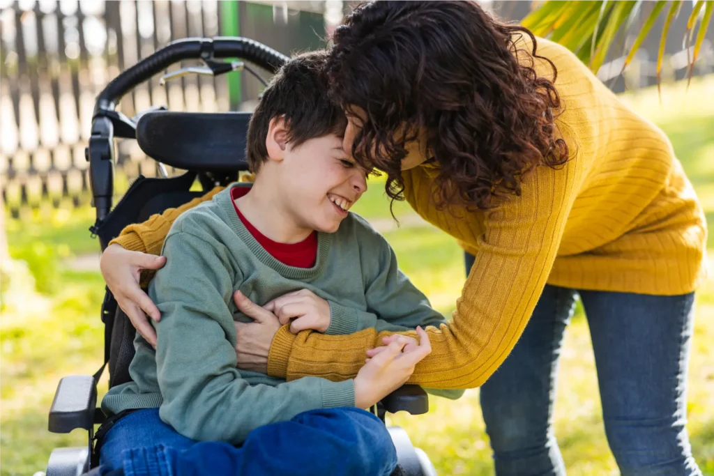 Parent comforting and supporting a child with additional mobility needs outdoors